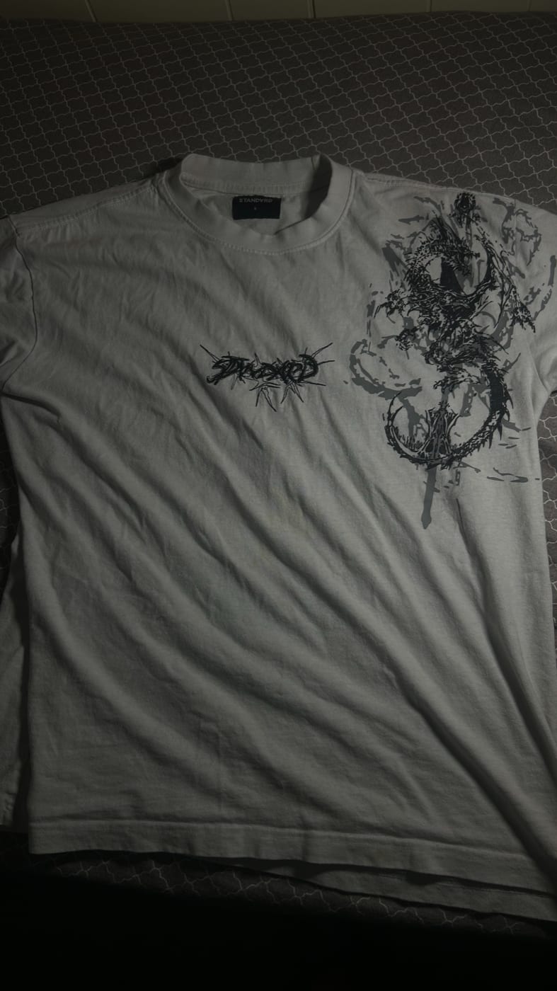 White Standard tee, front: a spiky logo on the chest and a dragon print over the right shoulder